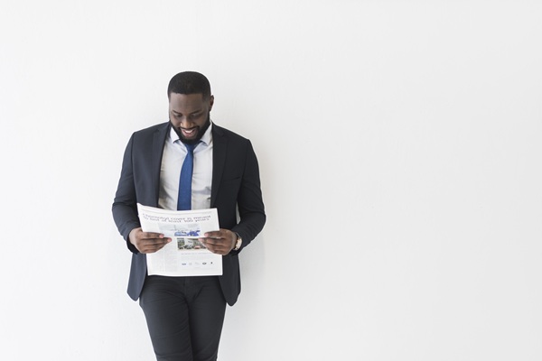 cheerful-ethnic-businessman-with-newspaper
